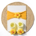 Detail of baby headband and socks set featuring 3D knit flowers on orange fabric - Earthy Yellow