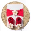 Macro view of red rib-knit baby headband and socks with cream fabric flower accents - Red
