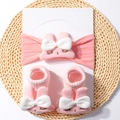 Detailed view of pink nylon baby headband and socks set with 3D bunny and bow on a mat - Pink