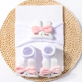 Detail of baby headband and socks set featuring plush bunny ears with pink bows - White