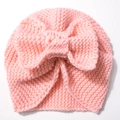 Detail of soft pink knitted baby hat featuring a large decorative knotted bow on top - Light Pink