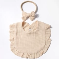 Dettaglio della bavaglia in garza di cotone beige con volant e fascia per capelli coordinata - Caffè Chiaro