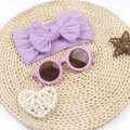 Flachbild von lila Strick-Stirnband mit Schleife und runder Sonnenbrille auf Strohmatte - Lila
