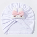 Detail of baby turban hat with pink bow and rabbit embroidery on white cotton fabric - White