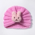 Detailed close-up of a pink knitted baby hat with cute plush bunny decor and spiral knit - Pink