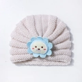 Detailed close-up of beige baby knit hat with a cute cartoon lion embroidery patch - Beige