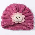 Détail d'un bonnet tricoté rose foncé pour bébé avec applique fleur de lion - Vieux rose