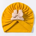Close-up of yellow baby turban hat featuring pink bow and eyelash embroidery details - Yellow