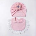 Dettaglio di cappellino neonato rosa in maglia e bavaglino con pizzo e fiori - Rosa