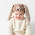 Detail der Baby-Strickmütze mit süßen Hasenohren, bunter Stickerei und weicher Materialstruktur - Kaffeebraun