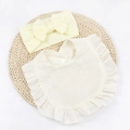 Close-up of ruffled off-white muslin baby bib and pale yellow bow headband set - Beige