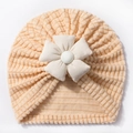 Primer plano del gorro turbante para bebé con tejido de punto gofrado y una gran flor de tela - Beige