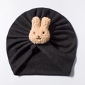 Detail view of the black baby turban hat featuring a beige plush rabbit and pleated texture - Black