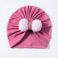 Detail einer Baby-Turbanmütze mit rosa Spitzenblumenbogen und gefaltetem Baumwollstoff - Rosenrot