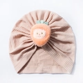 Close-up of pink waffle knit baby hat with a cute orange plush fruit smiling face emoji - Light Coffee