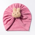 Detailed view of pink knitted baby turban hat with a plush beige bunny ornament - Dust Rose