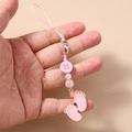 Detailed view of handmade pink beaded phone strap with paw pendants and woven cord - Pink