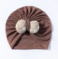 Detail of baby turban hat showing the soft knit fabric and embroidered floral bow - Brown