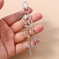 Detailed view of silver cross keychain with rhinestones and beads held in hand - Silver Infinity Cross