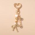Détail du porte-clés cœur doré avec perles et pendentif nœud serti de cristaux - Nœud Motif Cœur