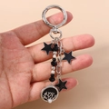 Detalle del llavero moderno con colgantes de estrellas negras y disco de coral calado - Árbol de la Vida Redondo Plata Negro