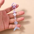 Detail of mermaid tail keychain with purple heart clasp and iridescent beads - Purple