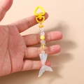 Macro detail of mermaid tail keychain with yellow beads and heart carabiner - Yellow