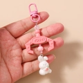 Detailed close-up of a plush white bunny and pink plastic claw keychain handheld view - Pink Rabbit