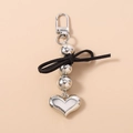 Detail of silver heart keychain with metal beads and a black ribbon bow charm - Silver
