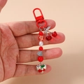 Detail eines Kirsch-Schlüsselanhängers mit rotem Karabiner und Perlen auf rosa Grund - Silber Herz Kirsche Perlen