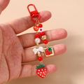 Detailed view of beaded strawberry keychain with red lobster clasp and white ribbon charm - Strawberry Bowknot Pearl
