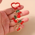 Detail of a red enamel cherry keychain with gold heart clasp and multi-layer bead accents - Cherry Red Ball
