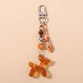 Detailed view of amber resin balloon dog keychain with beaded strap and croissant charm - Balloon Dog