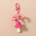 Detailed view of a pink claw machine keychain with a red polka dot mushroom pendant - Pink