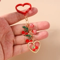 Detail of red cherry keychain featuring enamel charms and striped beads held by hand - Cherry Red and White Striped Ball