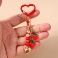 Detailed view of red strawberry beaded keychain with gold heart clasp and charms - Strawberry Heart Beaded