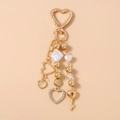 Detalle de llavero de corazón dorado con pedrería perlas y colgante de llave para bolso - Dije pavé de corazón hueco
