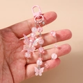 Detail of pink beaded butterfly charm with acrylic heart pendant and metal clasp - Pink