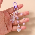 Close-up of a handmade purple beaded butterfly keychain with frosted metal clasp - Purple