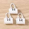 Macro detail of white quilted handbag charms with black bows and curved handles for DIY jewelry - 5 Pieces / White