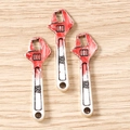 Macro detail of miniature wrench charms with red accents and RF engraving for DIY jewelry - 10 Pieces Pack / Wrench Style