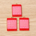 Detailed close-up of red and pink puzzle-themed alloy charms with gold-tone metal loops - Red