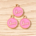 Detailed macro view of three pink enamel Love round charms with gold edges for DIY jewelry - LOVE Letter Round Tag (3206) / 10 Pieces Pack / Rose Red