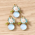 Détail de pendentifs floraux avec perles et globes bleus sur fond de bois clair - Fleur / Lot de 10 / Bleu