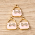 Detailed view of pink enamel handbag charms with crystal bows and gold alloy plating - Pink