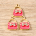 Macro shot of three pink handbag pendants with rhinestone bows for DIY jewelry making - Rose Red