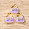 Detailed view of light purple enamel handbag charms with gold-toned bow and crystal inlay - Purple