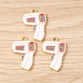 Detailed macro shot of three thermometer-shaped alloy pendants with gold plating and white enamel - 10 Pieces Pack / White