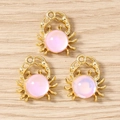 Dettaglio di ciondoli a forma di granchio in metallo dorato e opale sintetico rosa - Oro Rosa