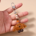 Close-up of cute croissant keychain with a smiley face, colorful beads, and silver metal clasp - Croissant